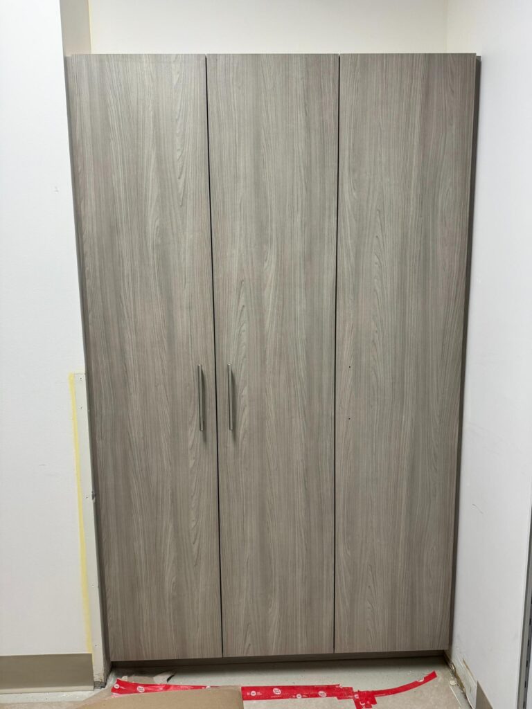 Tall woodgrain cabinet with flat-panel doors during installation