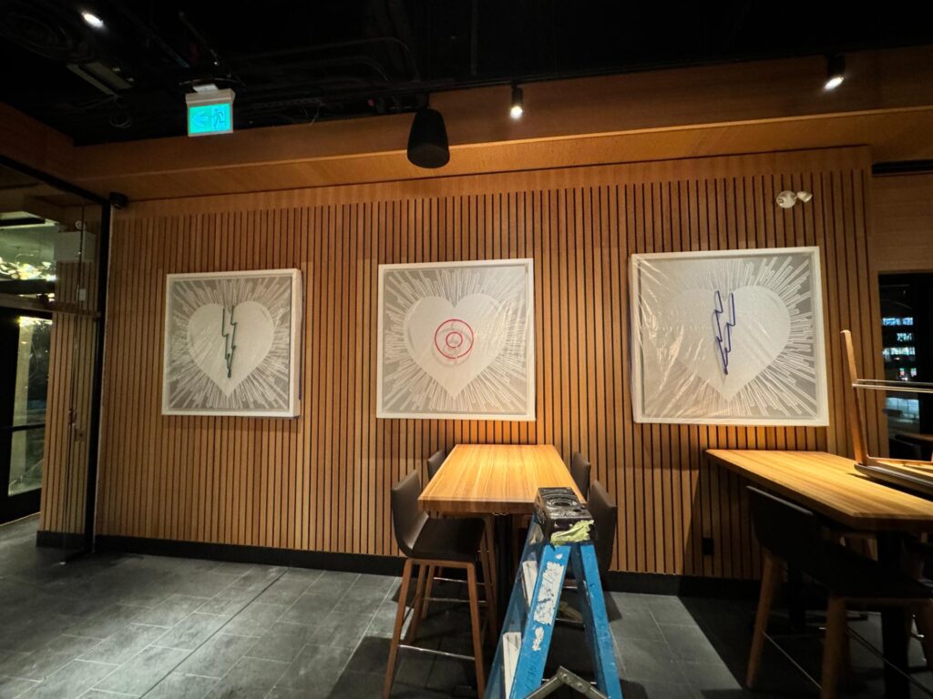 Wood slat feature wall with framed artwork and high-top tables in a restaurant
