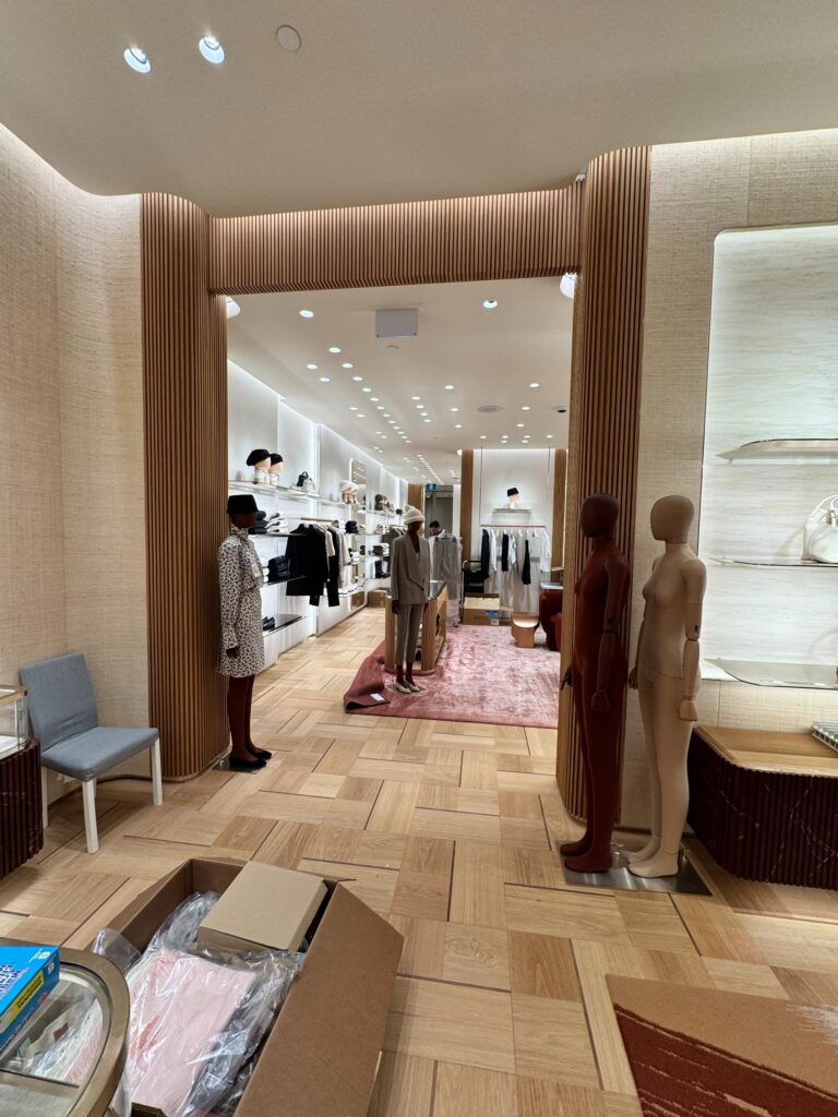 Boutique entrance with a curved wood slat portal and lit shelving
