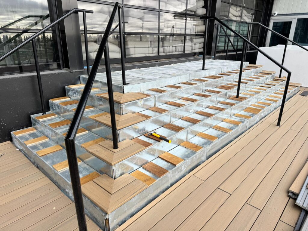 Composite deck stairs with black metal railings during construction