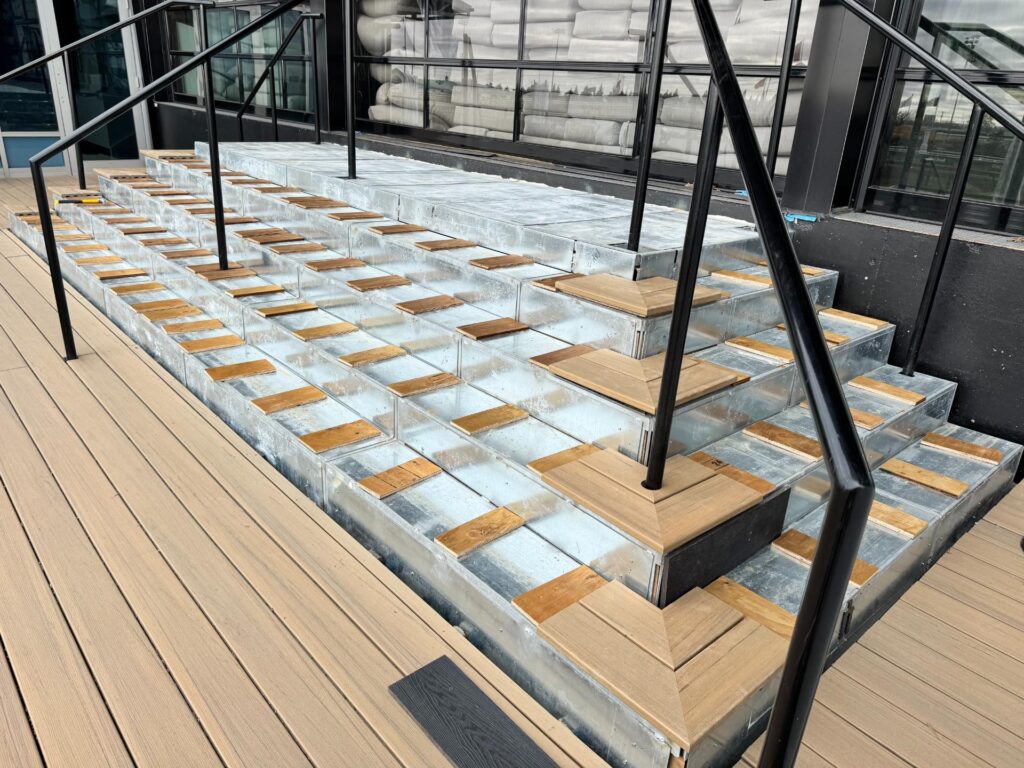 Composite deck stair landing with black metal handrails