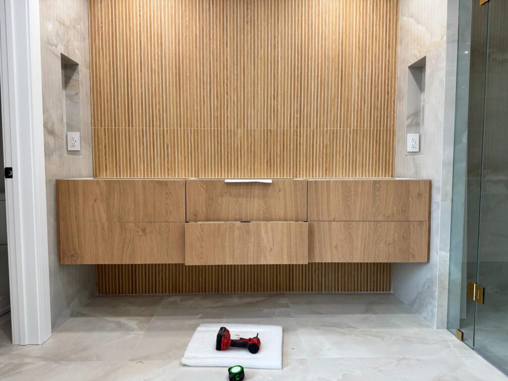 Floating oak vanity in front of a wood slat feature wall in a bathroom