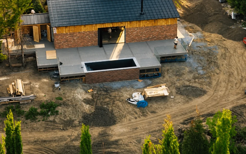 Aerial view of a large deck structure with an inset hot tub area beside a house