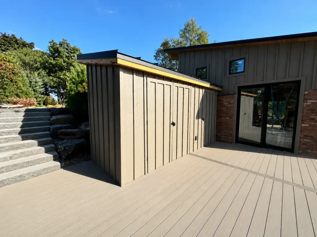 Board-and-batten storage structure beside a composite deck and stone steps
