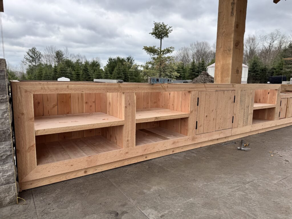 Cedar outdoor kitchen base with open shelving during construction
