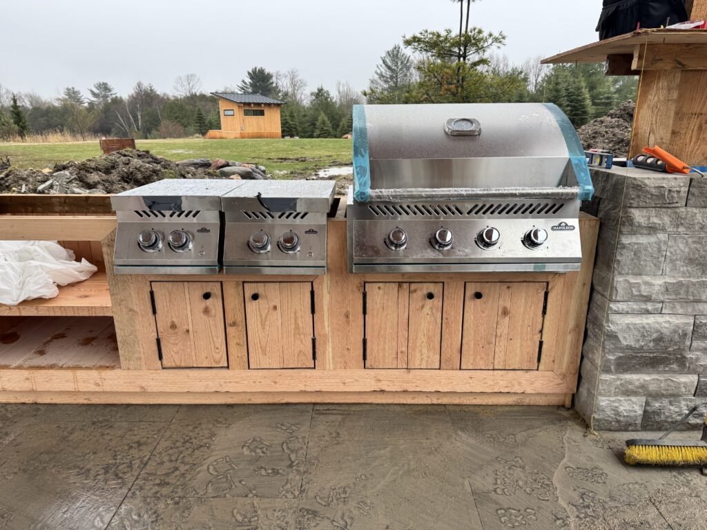 Outdoor kitchen with a built-in stainless grill, side burners and wood cabinetry