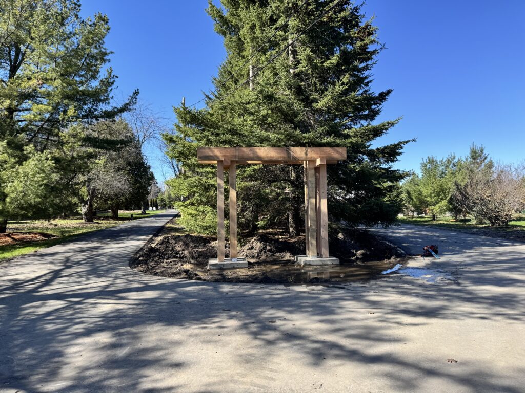 Heavy timber arbour at the entrance of a tree-lined driveway